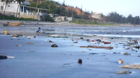 Child playing among plastic garbage and trash on sand on seashore. Pan shot Stock-Footage 50790618