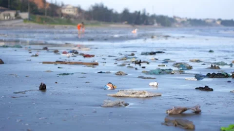 Child playing among plastic garbage and trash on sand on seashore. Pan shot Stock Footage 50791120