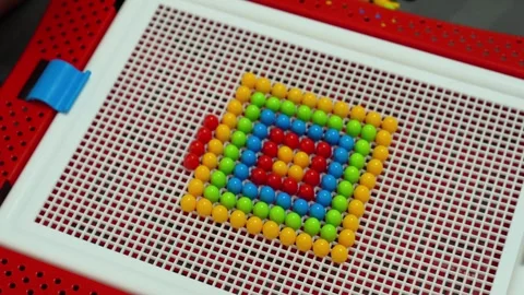 The child is playing and inserting red parts into the mosaic constructor. Close- Stock Footage 317917533