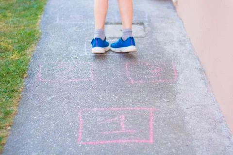 Child playing and jumping on numbers on the street 4 Stock Photos