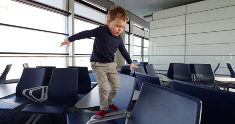 Child playing and jumping over airport seats, empty modern terminal Stock Footage 303325073