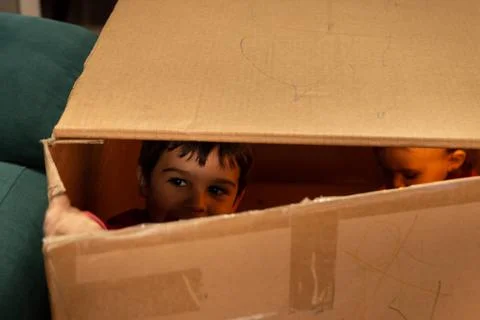 Child playing and looking through the crack of a cardboard box Stock Photos