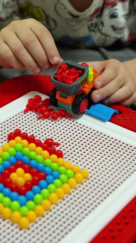 A child is playing and unloading mosaic pieces from a toy dump truck. Close-up Stock Footage 317917996