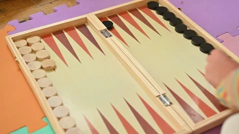 Child playing backgammon on a colorful patterned game board Stock Footage 290052158