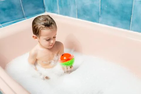 Child playing with a ball in a bubble bath Stock Photos