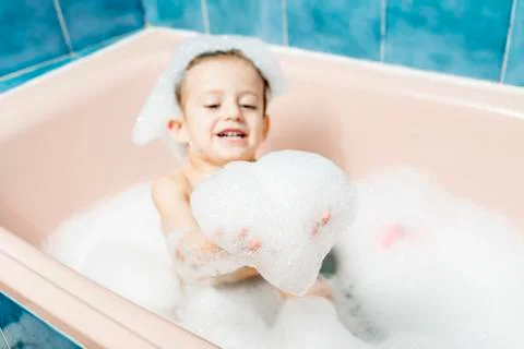 Child playing in the bath with the foam. Stock Photos