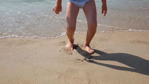 Child playing on a beach. Kid jumping in the waves. Sea vacation for family with Stock Footage 113819916
