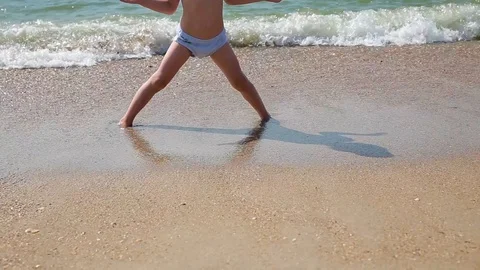 Child playing on a beach. Kid jumping in the waves. Sea vacation for family with Stock Footage 113819969