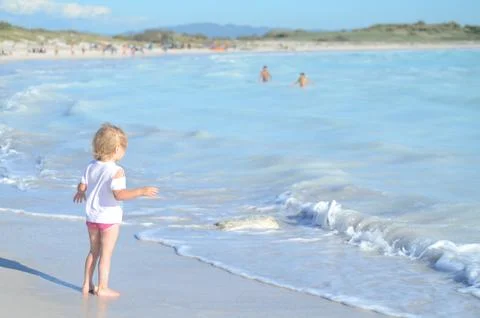 Child Playing at the Beach with Waves in the Background Stock Photos