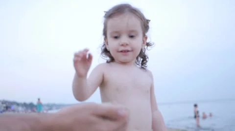 Child Playing on the Beach while Father Show how Sand Pours from Hands Stock Footage 65525328