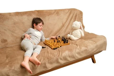 Child playing chess on sofa with plush rabbit toy isolated on white backgro.. Stock Photos
