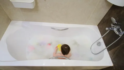 Child playing with colorful toy in bubble bath at home. Toddler sitting in Stock Footage 343166936
