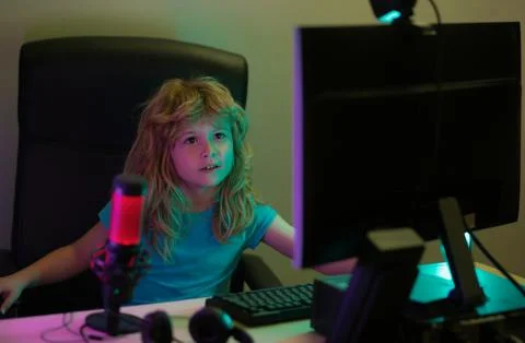 Child playing computer games or studying on pc computer. Kid gamer on night neon 写真素材