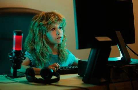 Child playing computer games or studying on pc computer. Kid gamer on night neon Stock Photos