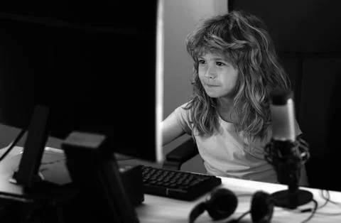 Child playing computer games or studying on pc computer. Kid gamer on night neon Stock Photos