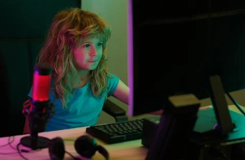Child playing computer games or studying on pc computer. Kid gamer on night neon Stock Photos
