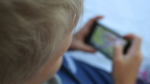 Child playing computer games using modern black smart phone Stock Footage 94772133
