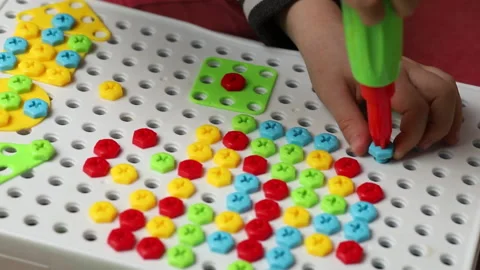 A child is playing with a construction constructor. Twists colored plastic Stock Footage 233709457