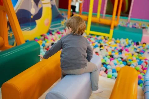 Child playing on cushioned rollers inside a bright indoor play area Stock Photos