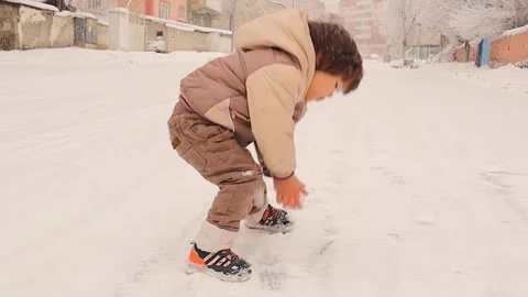 Child Playing in Falling Snow, Making Snowballs, and Throwing at Dad Stock Footage 295757827