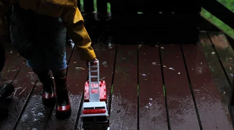 Child playing with Fire engine in the rain Stock Footage 37208431