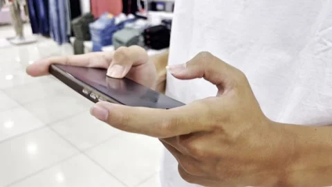 A child is playing a game on his cell phone in a shopping mall. Vidéo 340718594