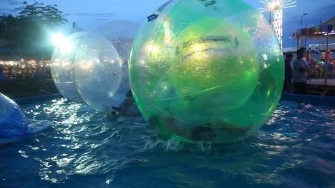 Child playing Giant Bubble Ball Orb Walking on Water in Theme Park. Stock Footage 77679402