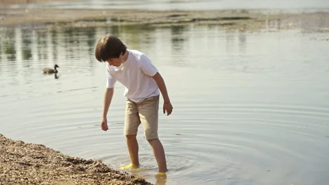 A Child Playing Joyfully by the Water Capturing Wonderful Moments in Natures Stock Footage 313333685