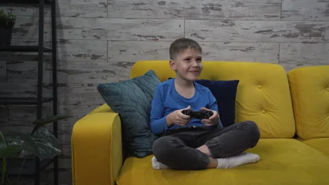 Child playing with a joystick while sitting on the couch. Mom takes the joystick Stock Footage 259681802