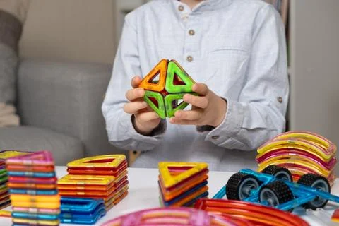 Child playing with magnetic constructor, hands close-up. Stock Photos