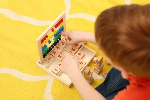 Child playing with math game kit on floor, above view. Learning mathematics.. Stock Photos
