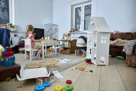 Child Playing in Messy Room Surrounded by Toys Stock Photos