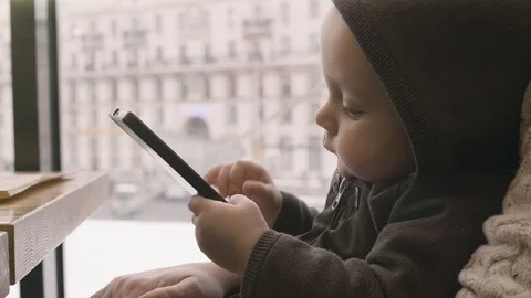 Child Playing with Mobile Phone on the Table. Infant hands texting on smartphone Video stock 86582403