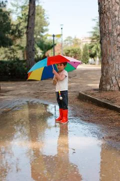 Child playing in mud puddle wearing rain boots Stock Photos