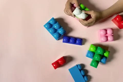 Child playing with multi-colored geometric toy figures on a light table close up Stock Photos