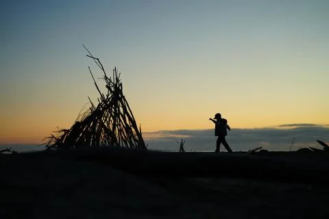 Child Playing Near Teepee Structure at Sunset 스톡 사진