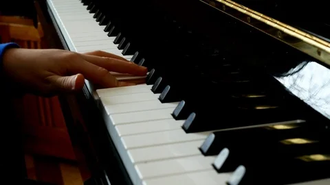 Child playing piano. Close up side view of young hands and fingers on the keys. Stock Footage 105628564