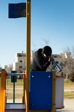 Child playing pirate looking through telescope at playground Stock Photos