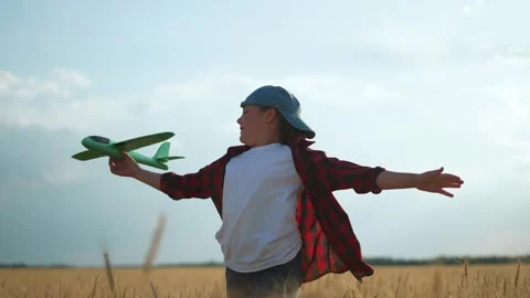 Child playing with plane at sunset. Kid runs with toy plane in field. Happy Stock Footage 345336484