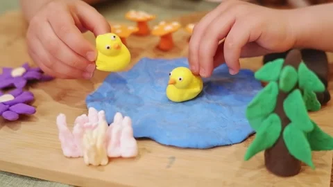 Child playing with plasticine ducks in imaginary pond Stock Footage 311436971