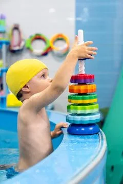 Child playing in pool, stacking colorful plastic rings onto vertical rod du.. Stock Photos