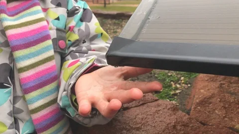 Child Playing with Rain Drops Falling on Her Hand from the Roof Drain Stock Footage 123723649