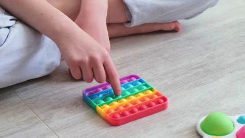 Child playing with rainbow popit. Modern silicone toy, trend 2021. Antistress Stock Footage 155374189