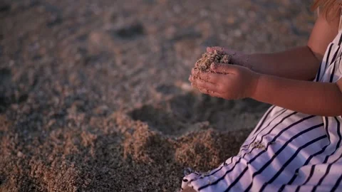Child playing with sand on the beach during sunset Видео 341119790
