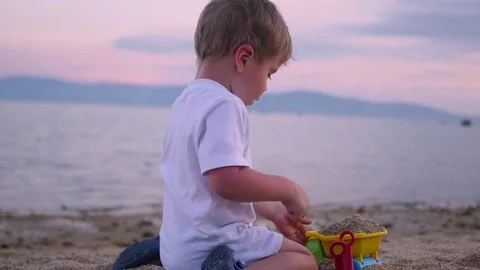 Child playing with sand on the beach at sunset time Vidéo 74540825