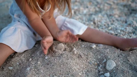 Child Playing with Sand on the Beach at Sunset Видео 341120259
