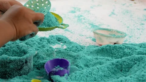 Child playing in the sand. Close-up of a boy's hand playing with turquoise sand. Stock Footage 306774742