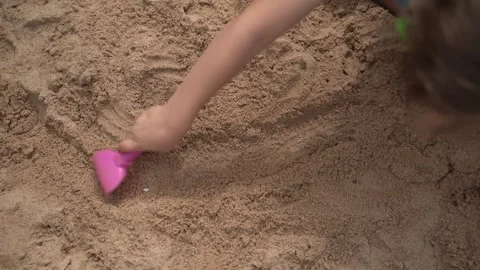 Child playing in sandbox with rake, building castles. Close-up video. Video stock 312048923