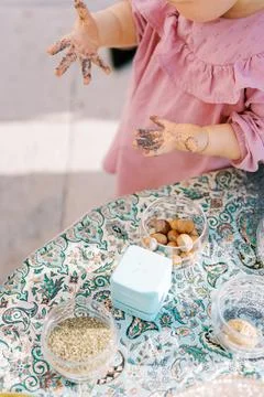 Child Playing With Seeds and Nuts on Patterned Tablecloth Stock Photos