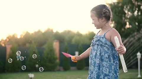 Child playing with soap bubbles in summer on the grass at sunset close-up. Stock Footage 271305659